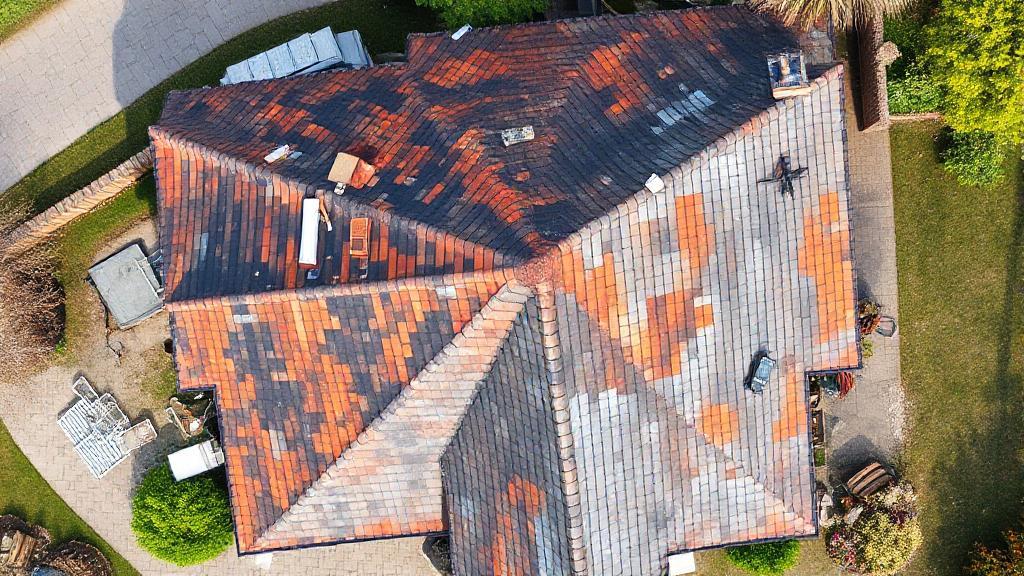 A detailed aerial view of a house roof under renovation, with workers and materials visible, illustrating the process and scale of roof replacement.