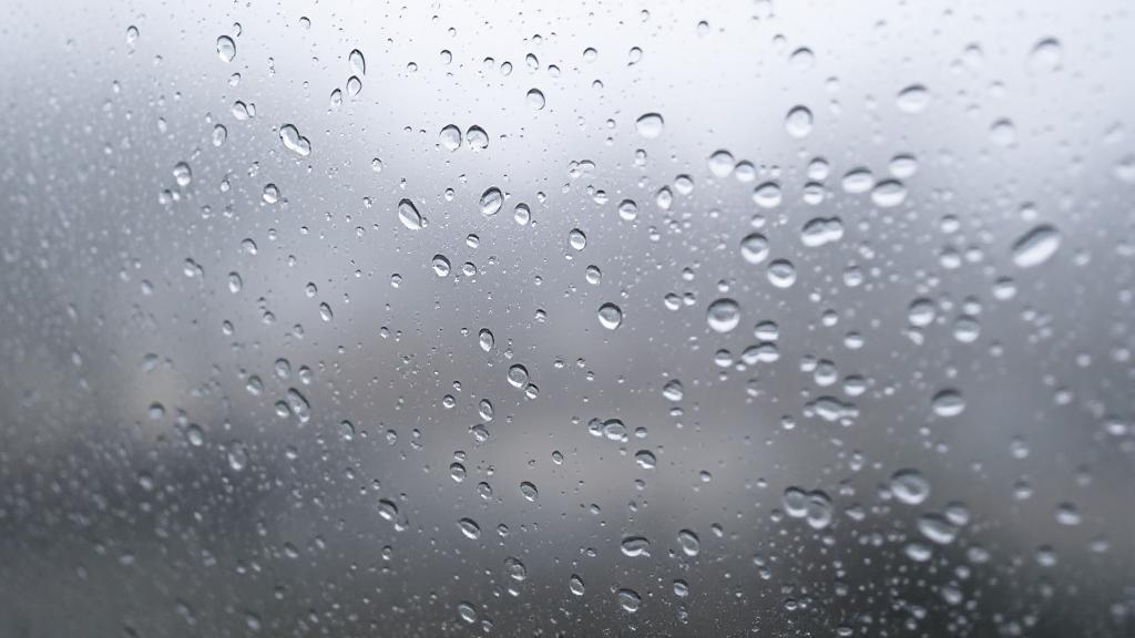 A close-up image of a foggy window with water droplets, illustrating indoor window condensation.