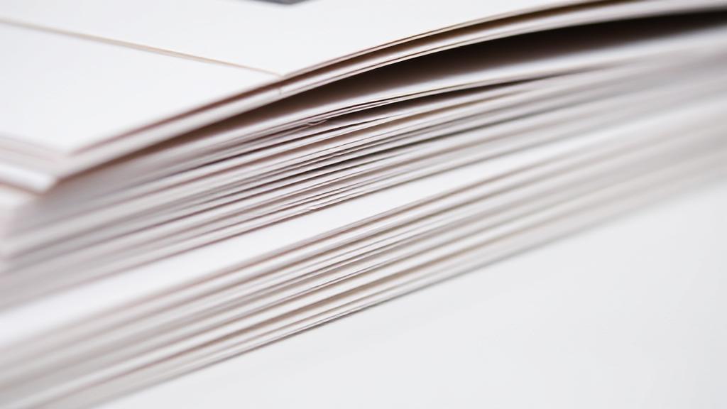 A close-up image of a neatly stacked set of saddle-stitched booklets, showcasing the precision and elegance of the binding technique.