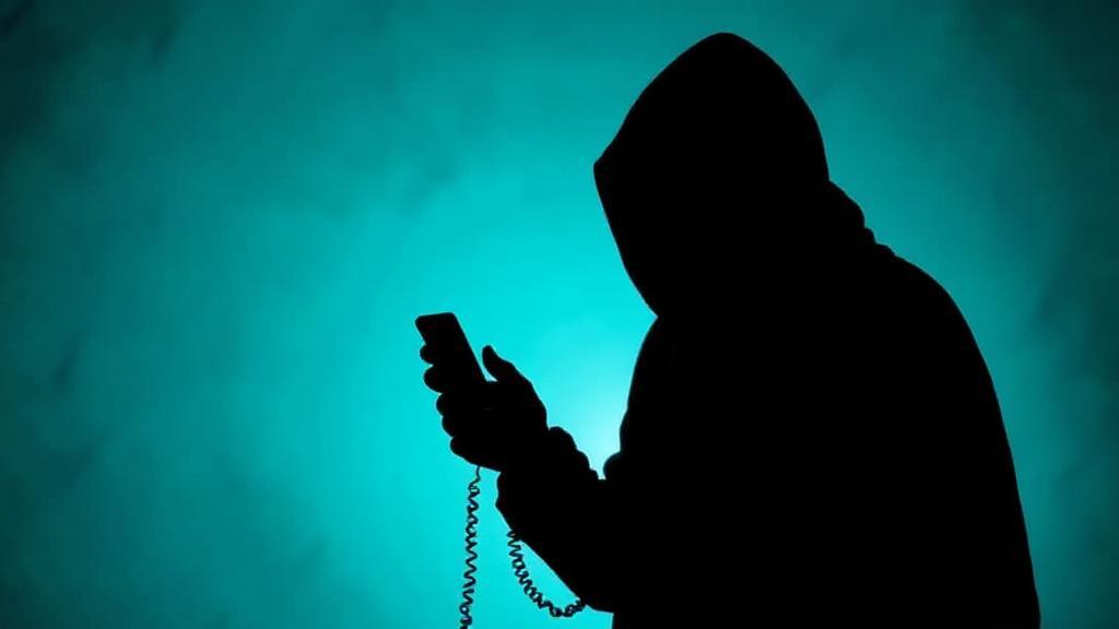 A tense, shadowy figure holding a phone, symbolizing the anxiety and secrecy surrounding blackmail situations.